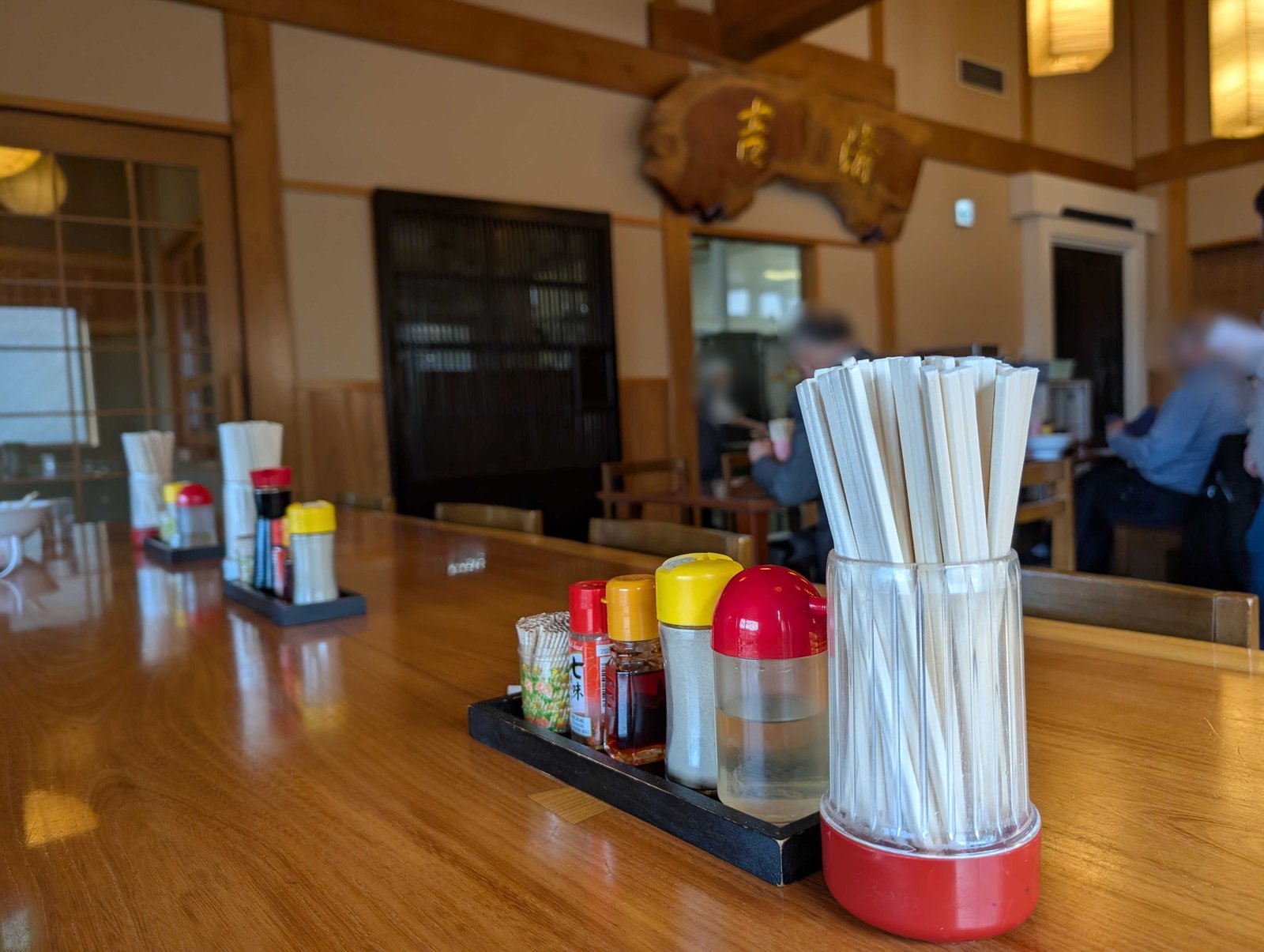 清吉そばや本店の店内。広いテーブル席と卓上の薬味