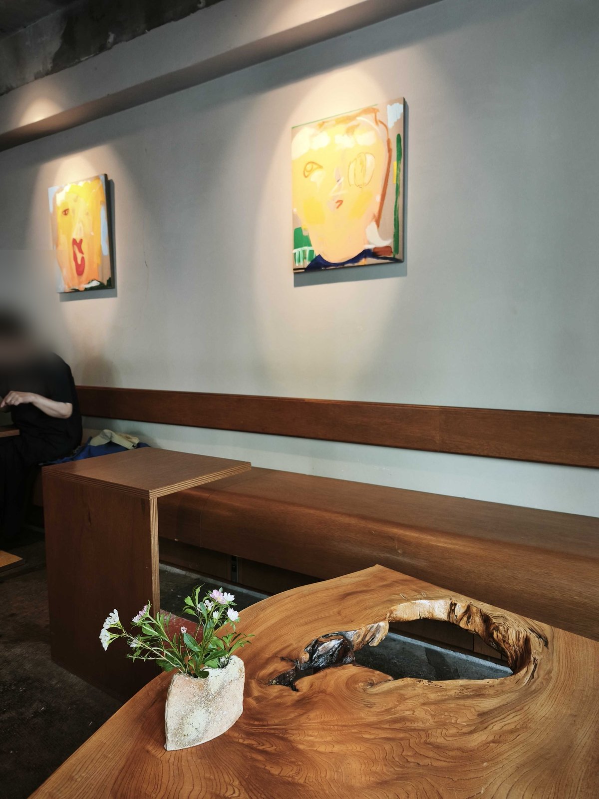 店内の壁に飾られたアートと木製テーブルの一輪挿し
