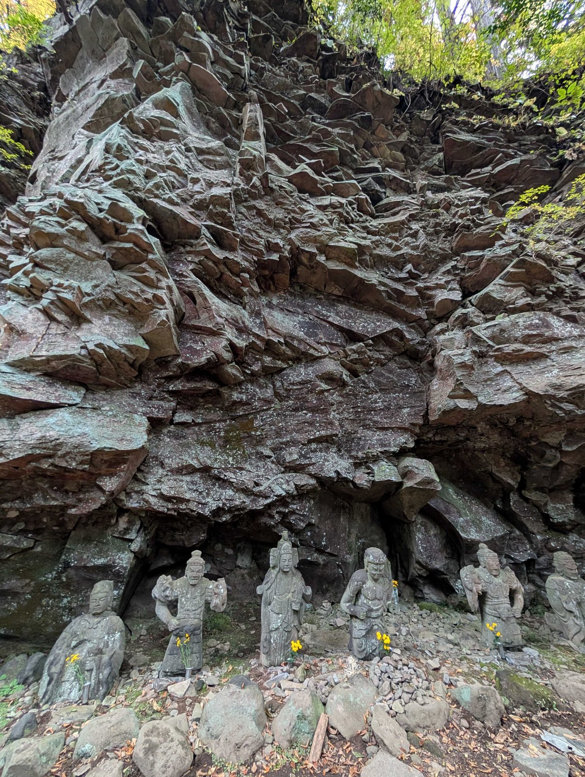 仏岩。崩れた岩が積み上がり、その根元に石の像が並んでいる